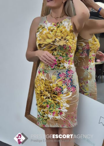 Woman in floral dress admires reflection in mirror.