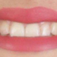 Close-up of person smiling with red lipstick.